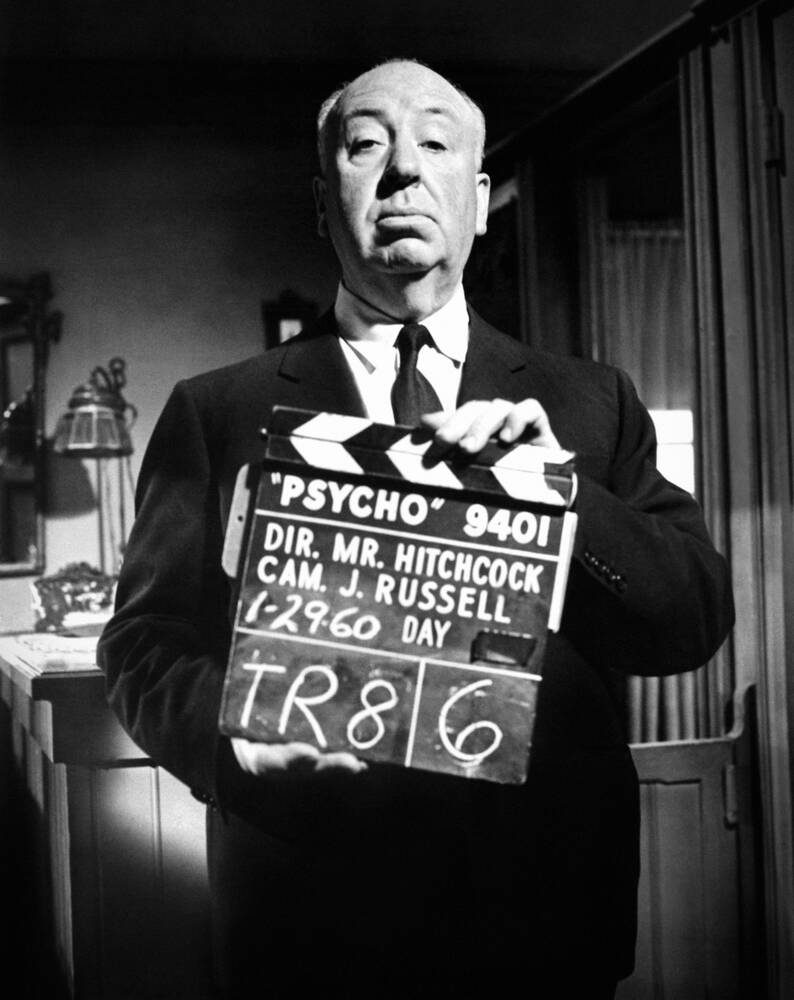 Alfred Hitchcock holding a clapperboard on the set of Psycho