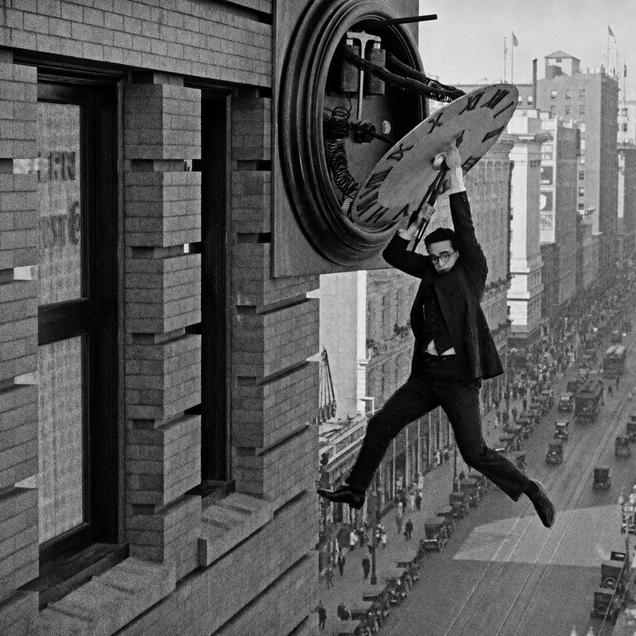 Harold Lloyd hanging from a clock face above a city street